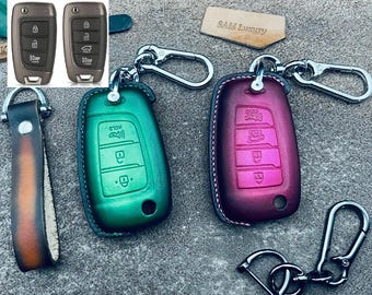 Puede incluir: Dos llaveros con llaveros de cuero. Los llaveros son verde y rosa con un anillo de metal plateado. Los llaveros son de cuero marrón con un cierre de metal plateado. El texto "SAM Luxury" es visible en una pequeña etiqueta marrón.