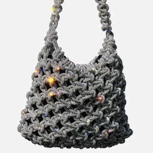 Könnte beinhalten: Eine silberne Handtasche mit einer Kettenriemenschultertasche, die vollständig mit Strasssteinen besetzt ist. Die Tasche ist aus Netzmaterial mit einem Knotenmuster.
