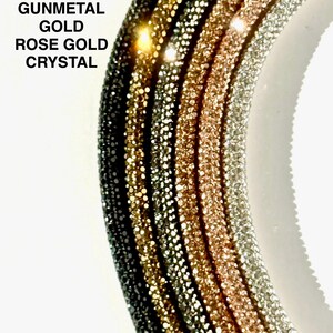 May include: Five different colored rhinestone chains, from left to right: black, bronze, gunmetal, gold, and rose gold. The chains are arranged in a semi-circle.