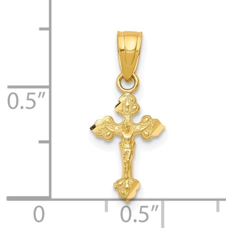 May include: A gold crucifix pendant. The pendant shows a detailed depiction of Jesus on the cross. The cross measures approximately 1.3 cm in length and is suspended from a small loop.