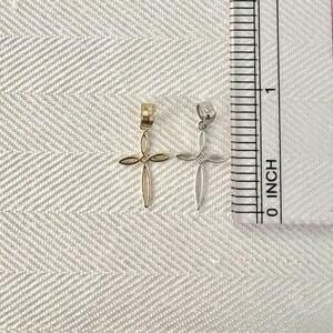 Puede incluir: Dos peque&ntilde;os colgantes de cruz, uno dorado y otro plateado, se muestran junto a una regla en pulgadas. Las cruces tienen un dise&ntilde;o abierto y delicado. La regla muestra medidas en pulgadas.
