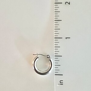 K&ouml;nnte beinhalten: Ein einzelner, gl&auml;nzender silberner Creolen-Ohrring. Der Ohrring hat einen Durchmesser von ca. 1,9 cm. Der Ohrring wird vor einem wei&szlig;en Hintergrund mit einem Zollstock zur Gr&ouml;&szlig;enbestimmung gezeigt.