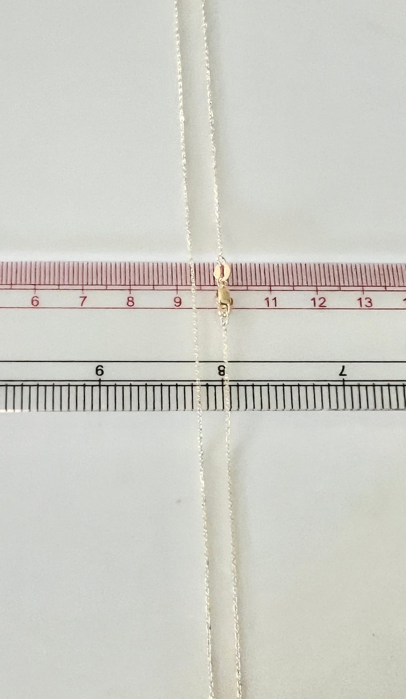 May include: A silver chain necklace with a gold clasp. The chain is approximately 11 inches long.