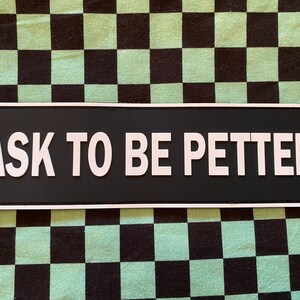 Puede incluir: Un letrero en blanco y negro con el texto "ASK TO BE PETTED" en letras blancas sobre un fondo negro.