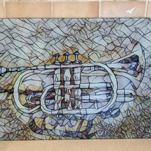 May include: A glass chopping board featuring a stained glass design of a silver trumpet. The trumpet is surrounded by a colourful, abstract background.