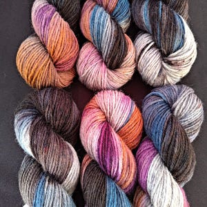 Handgefärbtes 5fach Superwash-Wollgarn ""Orpheus"" 50g/144 m in lila, schwarz, blau, orange und grau, 100% Superwash-Wolle."