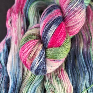 Può includere: Primo piano di gomitoli di filato colorati. Il filato presenta un vivace mix di tonalità rosa, blu, verdi e bianche. Il filato è morbido e sembra tinto a mano, perfetto per progetti di maglieria o uncinetto.