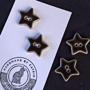 May include: Four star-shaped buttons with a dark brown and cream gradient finish, each featuring two center holes. Two buttons are attached to a white display card printed with a cat icon and the text HANDMADE BY CATKIN MADE WITH LOVE.