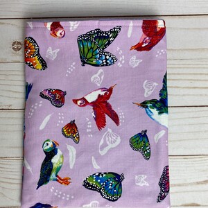 May include: A lavender fabric pouch with a colorful butterfly and bird print. The pouch features a variety of butterflies, birds, and feathers in shades of blue, green, red, orange, and yellow.