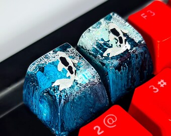 May include: Two blue and white keycaps with a koi fish design. The keycaps are on a black keyboard with red keys labeled with numbers and letters.