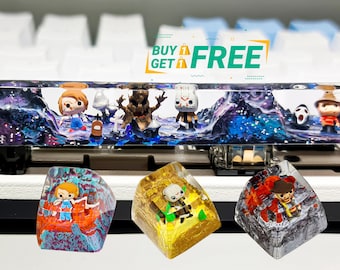 May include: Four colorful resin keycaps with different character designs. The keycaps are on a white keyboard with a blue and black resin keyboard keycap bar. The bar has a galaxy design with various characters embedded in the resin. The text "BUY 1 GET 1 FREE" is in a yellow banner above the keyboard.
