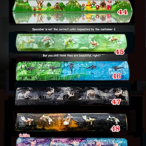 May include: A collection of six 6.25u resin mechanical keyboard spacebars labeled 44 through 49. Designs include a forest scene with characters, koi fish in green, whale sharks in blue, axolotls in black, koi in dark amber, and stingrays in purple.