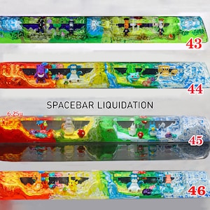Peut inclure: Quatre barres d'espace pour clavier mécanique en résine étiquetées 43, 44, 45 et 46. Chaque barre présente un paysage multicolore avec des figurines miniatures intégrées. Le texte SPACEBAR LIQUIDATION et 6.25u sont visibles sur l'image.
