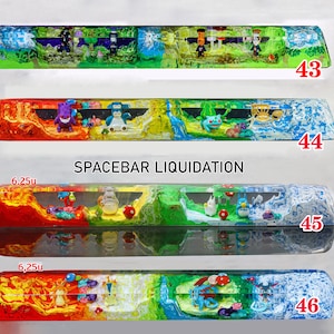 May include: Four custom resin mechanical keyboard spacebars labeled 43, 44, 45, and 46. Each bar features a multi-colored landscape with miniature figures embedded inside. The text SPACEBAR LIQUIDATION is centered above the third bar, with 6.25u indicated.