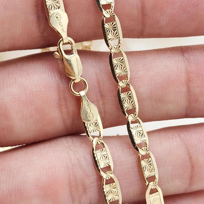 May include: A gold chain necklace with a detailed, patterned design. The chain is made of oval-shaped links.