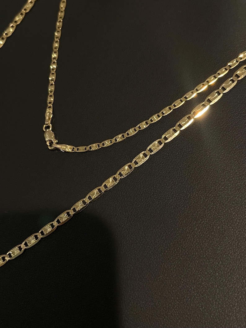 May include: A gold chain necklace with a mariner link design. The chain is made of solid gold and has a polished finish.
