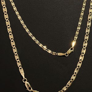 May include: A gold chain necklace with a mariner link design. The chain has a diamond-cut finish and is made of 14k gold.