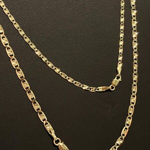 May include: A gold chain necklace with a mariner link design. The chain has a diamond-cut finish and is approximately 20 inches long.