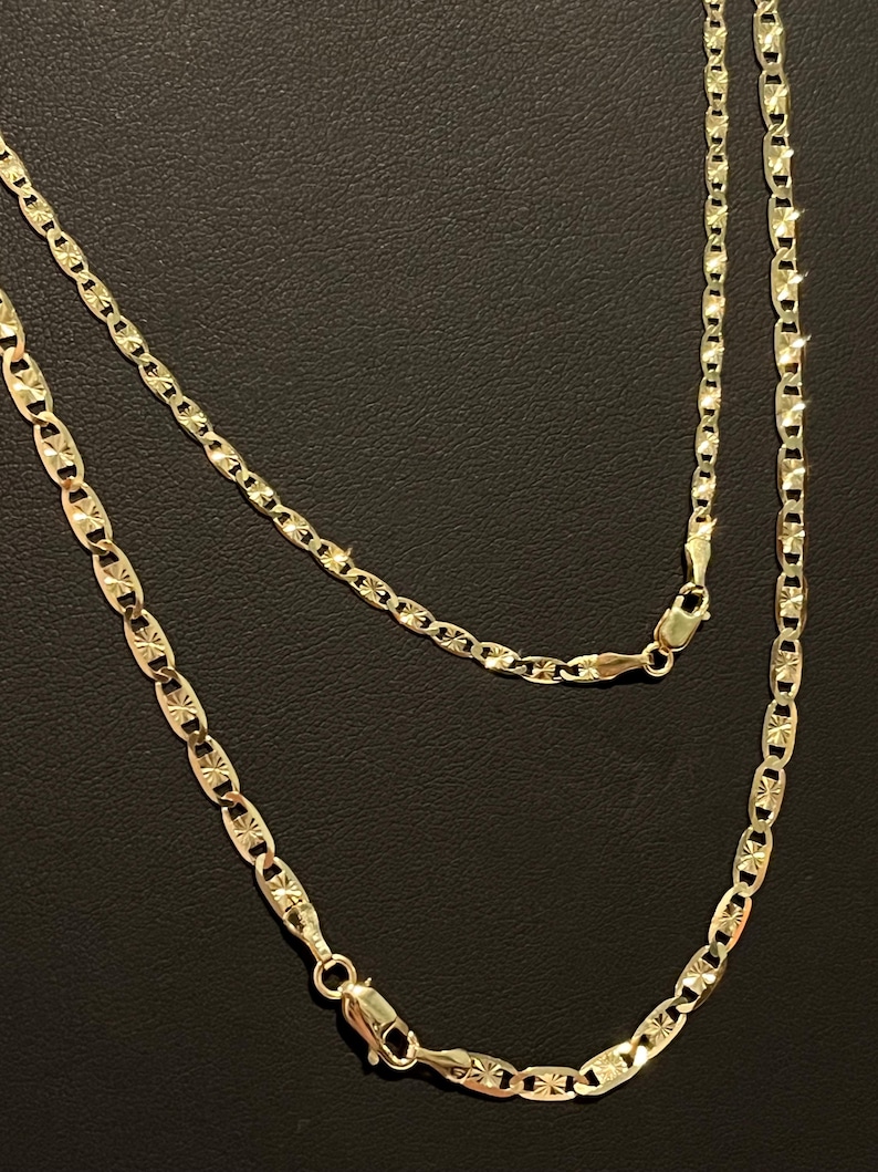 May include: A gold chain necklace with a mariner link design. The chain has a diamond-cut finish and is approximately 20 inches long.