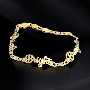 May include: A gold-colored bracelet with the name "Bright" and "Bray" in a cursive font. The bracelet has a chain-link design with a lobster clasp. The background is black.