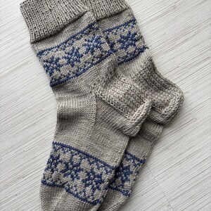 May include: A pair of grey knitted socks with a blue snowflake pattern.