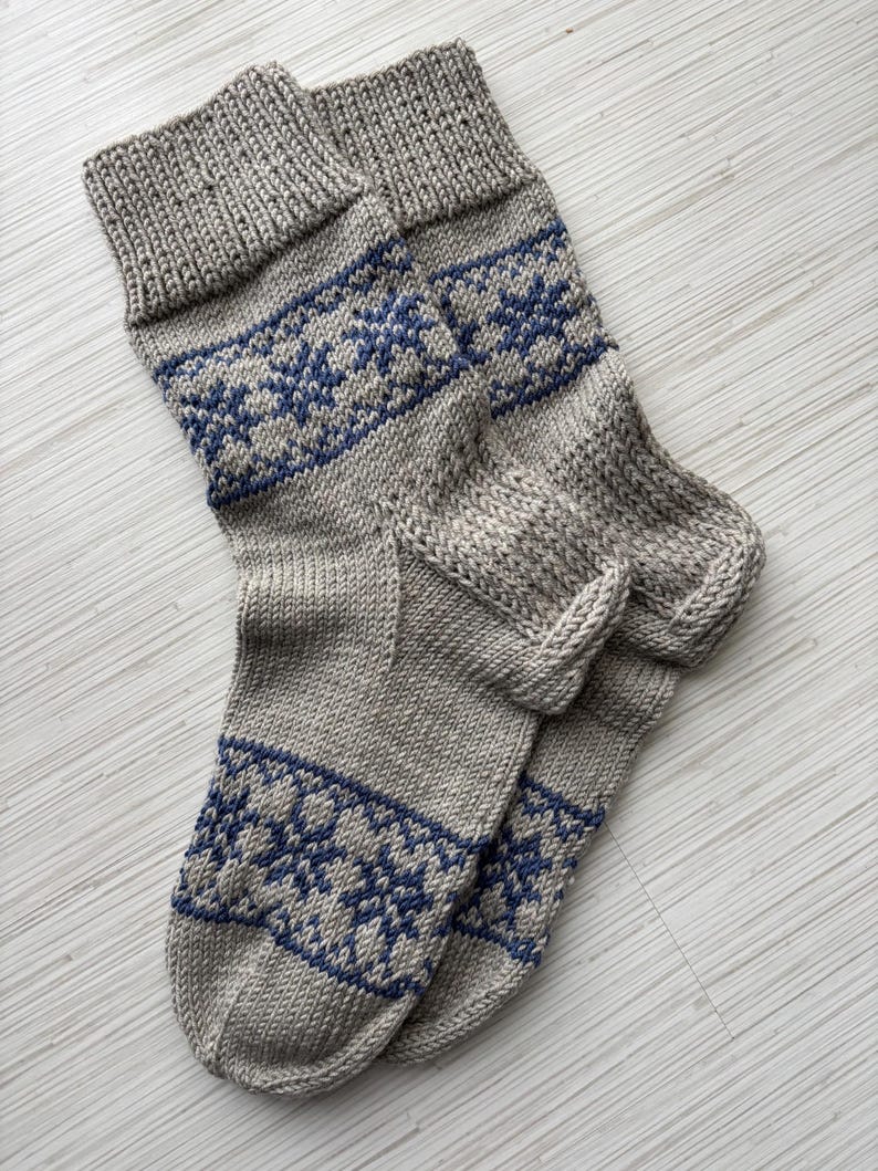 May include: A pair of grey knitted socks with a blue snowflake pattern.