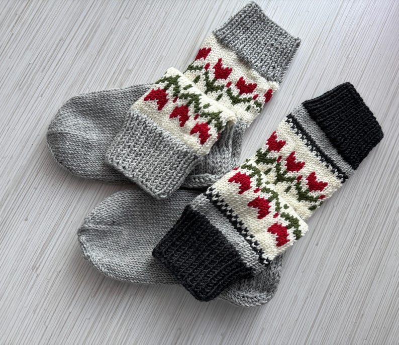 May include: A pair of gray and white knitted socks with a red and green floral pattern. The socks are made of a soft, comfortable material and are perfect for keeping your feet warm in the winter.