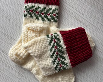 May include: A pair of hand-knitted Christmas stockings. The top cuff is a deep red, transitioning to a cream-colored body with a green and red fir tree pattern. The stockings are made of a thick, textured yarn.
