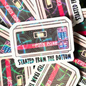 May include: A sticker featuring a vintage Easy-Bake Oven with a holographic effect. The sticker has the text "Started from the bottom" printed below the oven.