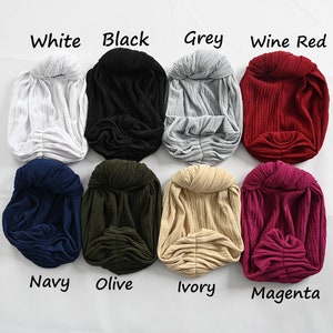 Puede incluir: Ocho diademas de turbante de diferentes colores, cada una con un nudo en la parte superior. Los colores son blanco, negro, gris, rojo vino, azul marino, oliva, marfil y magenta.
