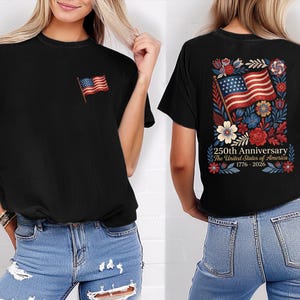 May include: Black t-shirt featuring a small American flag on the front and a larger design on the back. The back design includes an American flag, flowers, and text that reads "250th Anniversary The United States of America 1776-2026."