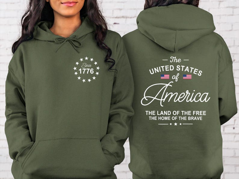 Pu&ograve; includere: Felpa con cappuccio verde oliva con tasca frontale e coulisse. La parte anteriore presenta un disegno bianco con il testo "Since 1776". Il retro mostra "The United States of America" con la bandiera americana e "The Land of the Free, The Home of the Brave".