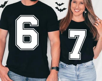 Puede incluir: Dos camisetas negras con grandes números blancos. Una muestra el número 6, la otra el 7. Los números tienen un diseño en negrita y contorneado. Las camisetas las llevan dos personas, lo que sugiere un conjunto a juego o un atuendo coordinado.
