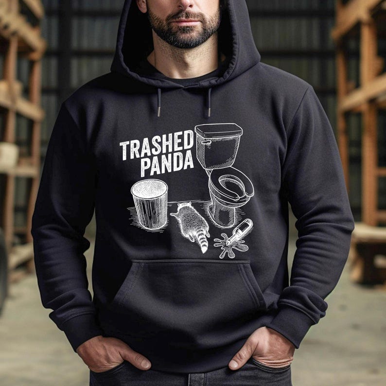 The image displays a raccoon lying face down on the floor in a comical pose. Surrounding items include a toilet, a garbage can, and a spilled glass bottle. The caption TRASHED PANDA is written in a distressed font, highlighting the drunk or hungover theme.