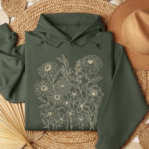 Hoodie with vintage pressed flowers arranged in retro botanical sketches. Cottagecore floral artwork creates a cozy, nature-inspired design. Ideal for gardening lovers, floral fashion fans, or anyone who enjoys unique boho designs.
