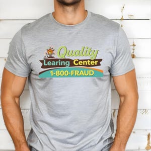 May include: A light gray t-shirt with the words "Quality Learing Center" and the phone number "1-800-FRAUD" printed on the front. The design includes a small house graphic and a brown banner.