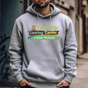 May include: A gray hooded sweatshirt with a front pocket. The sweatshirt features a graphic with the words "Quality Learing Center" and the phone number "1-800-FRAUD" in green, brown, and blue.