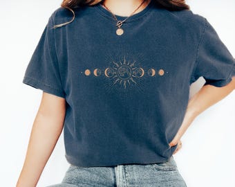May include: A navy blue t-shirt with a graphic of a sun and moon phases design. The graphic is in a light brown color.