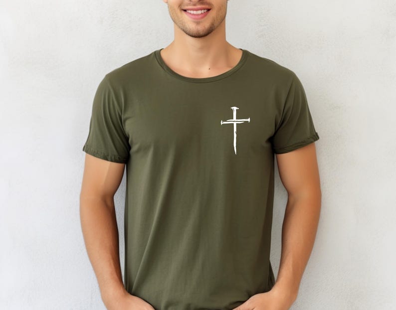 May include: A green t-shirt with a white cross design featuring nails. The cross is a simple design with a vertical line and a horizontal line, and the nails are represented by small circles.