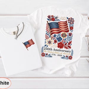 May include: Two white t-shirts. One features a small American flag graphic. The other has a larger design of the American flag surrounded by flowers and the text "250th Anniversary The United States of America 1776-2026".