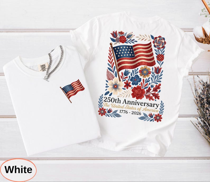 May include: Two white t-shirts. One features a small American flag graphic. The other has a larger design of the American flag surrounded by flowers and the text "250th Anniversary The United States of America 1776-2026".