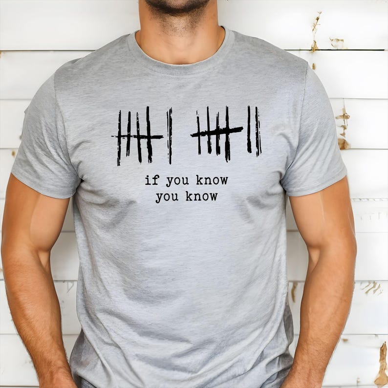 May include: A light gray t-shirt with the phrase "if you know you know" printed in black. The design includes two sets of tally marks, each with a line through them. The shirt is made of a soft material.