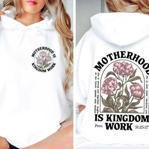 May include: White hoodie with the text "MOTHERHOOD IS KINGDOM WORK" and a floral design. The design is on the front and back of the hoodie. The back design includes the text "Prov. 31:25-27".
