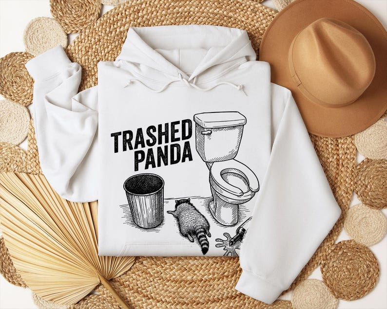 May include: White hoodie with a black and white illustration of a raccoon, a toilet, and a bin. The text "Trashed Panda" is printed above the graphic. The hoodie has a drawstring hood and long sleeves.