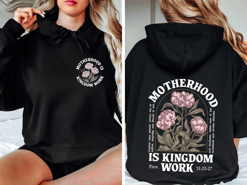 May include: Black hoodie with the text "MOTHERHOOD IS KINGDOM WORK" and a floral design. The design is on the front and back of the hoodie. The back of the hoodie also includes a Bible verse.
