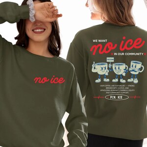May include: Olive green sweatshirt with the text "no ice" in red on the front. The back features the phrase "We want no ice in our community" in red, along with a graphic of three coffee cups and additional text.