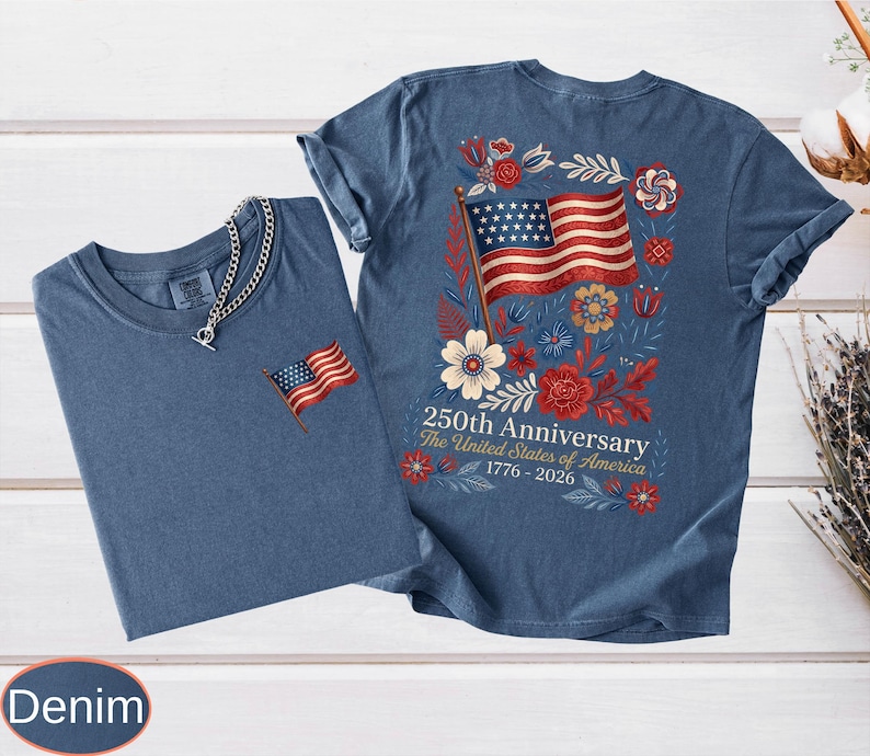 May include: Two denim blue t-shirts. One has a small embroidered American flag on the chest. The other has a large graphic on the back with an American flag, flowers, and text that reads "250th Anniversary The United States of America 1776-2026."