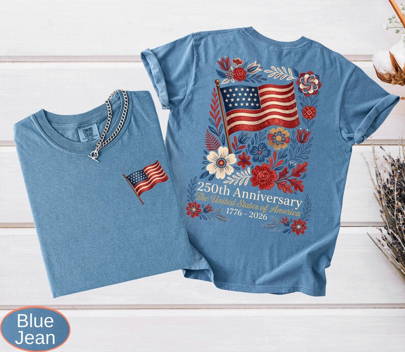 May include: Two blue jean t-shirts. One has a small embroidered American flag on the chest. The other has a large American flag design on the back, surrounded by flowers, with the text "250th Anniversary The United States of America 1776-2026."