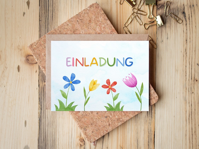May include: A white card with the word "EINLADUNG" in rainbow letters. The card is decorated with watercolor illustrations of flowers in blue, yellow, pink, and red.
