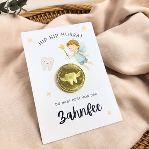 Könnte beinhalten: Eine weiße Karte mit dem Text "HIP HIP HURRA!" und "DU HAST POST VON DER ZAHNFEE". Sie zeigt eine Cartoon-Fee, einen lächelnden Zahn und eine Goldmünze mit einem Zahndesign. Die Karte ist mit gelben Sternen verziert.